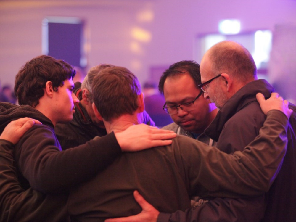Men praying for each other at a PK event