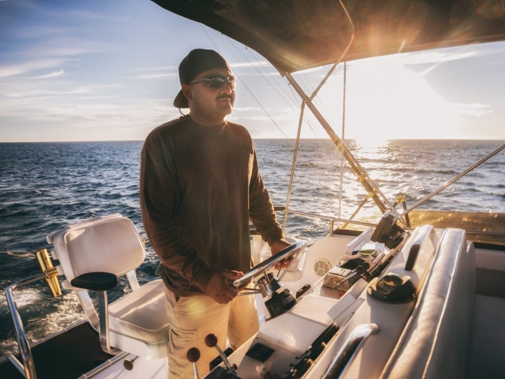 Man driving a boat looking for a place to fish, looking for a place to anchor his boat,