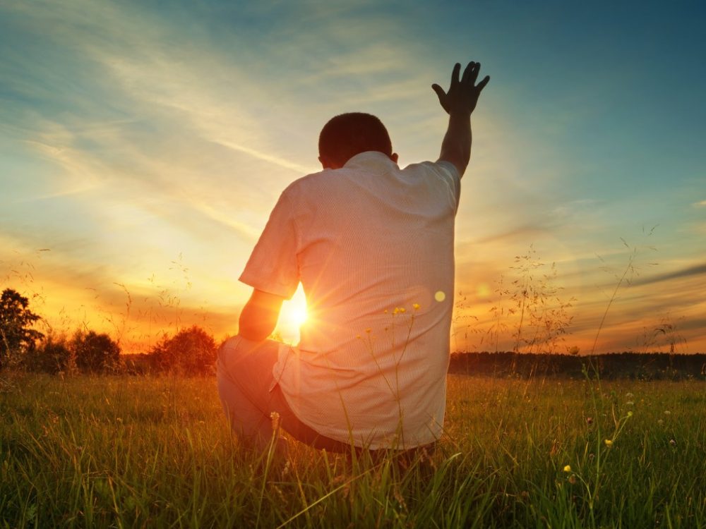 How We Can Position Ourselves to Call on the Father with Boldness, man kneeling with arm raised to God, calling out to God,